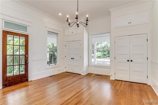 entryway with light wood-type flooring, plenty of natural light, and ornamental molding