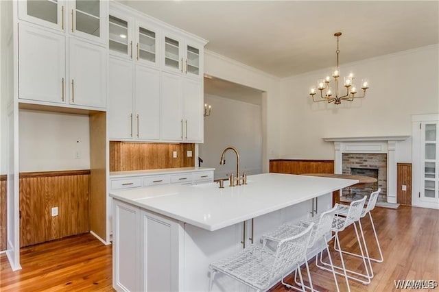 kitchen with white cabinets, decorative light fixtures, light hardwood / wood-style flooring, and a brick fireplace