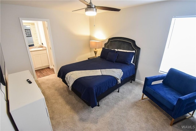 bedroom with ensuite bath, ceiling fan, sink, and light carpet