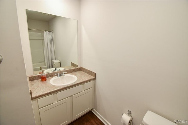 bathroom featuring hardwood / wood-style floors, vanity, toilet, and walk in shower