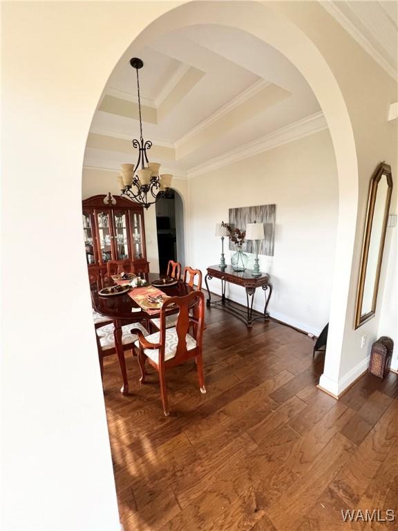 dining room featuring crown molding, dark hardwood / wood-style flooring, a raised ceiling, and a notable chandelier