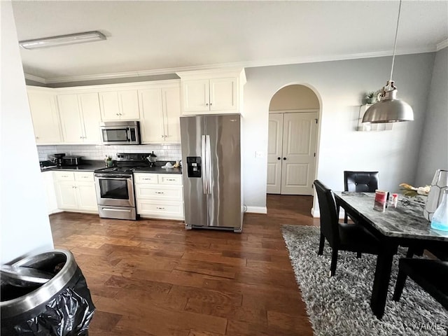 kitchen featuring dark wood-type flooring, white cabinetry, pendant lighting, stainless steel appliances, and decorative backsplash