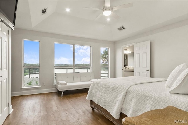 bedroom featuring hardwood / wood-style flooring, a raised ceiling, ceiling fan, and ensuite bathroom