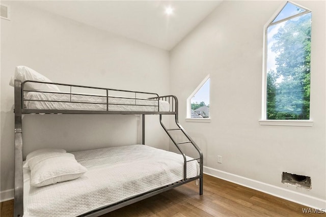 bedroom featuring hardwood / wood-style floors, multiple windows, and lofted ceiling