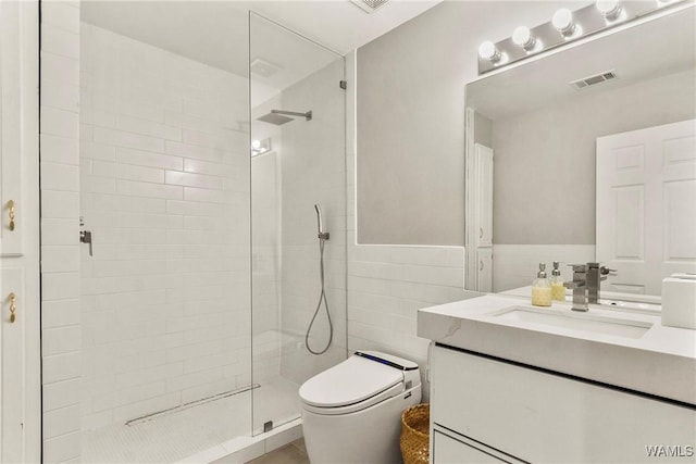 bathroom featuring a tile shower, vanity, tile walls, and toilet