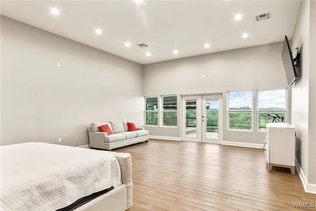 bedroom with access to exterior, french doors, a high ceiling, and light hardwood / wood-style flooring