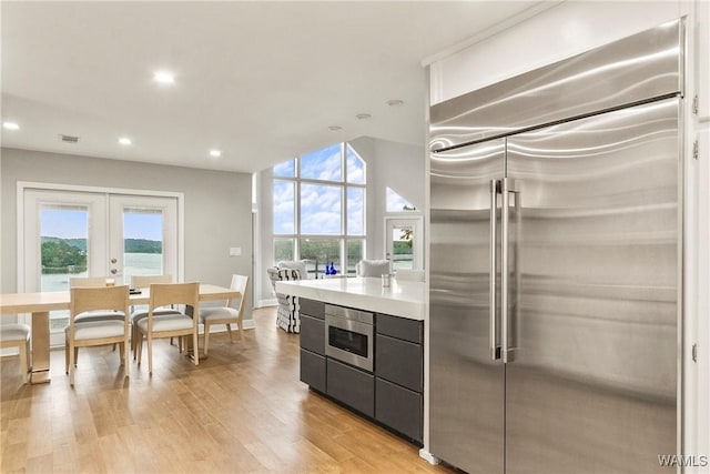 kitchen with french doors, built in appliances, and light hardwood / wood-style flooring