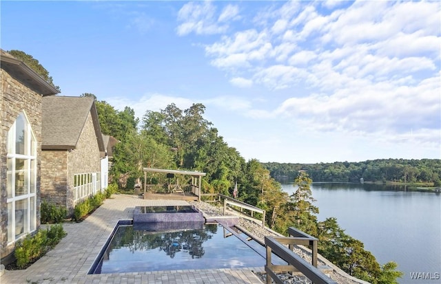 view of pool with a water view and a patio