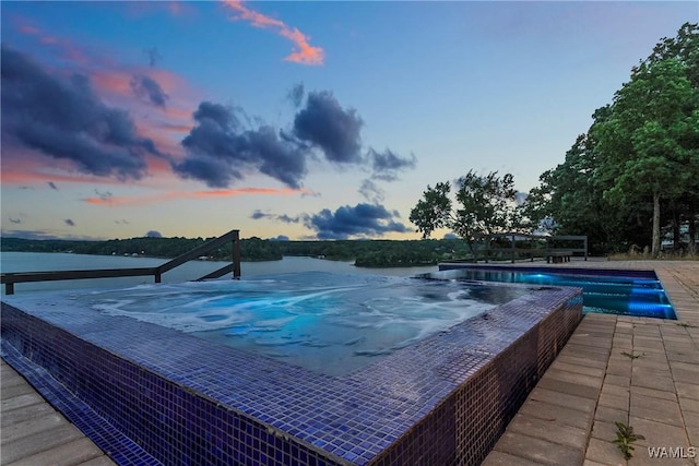 pool at dusk featuring a water view