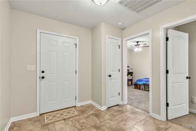 entryway with a textured ceiling, visible vents, and baseboards