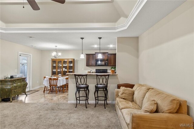 living room featuring light carpet, ceiling fan with notable chandelier, a raised ceiling, and baseboards