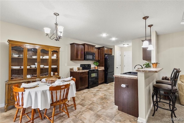 kitchen with dark brown cabinetry, a peninsula, a sink, black appliances, and a kitchen bar