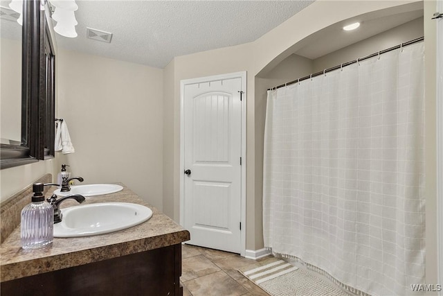 full bath with a textured ceiling, tile patterned flooring, a sink, and visible vents