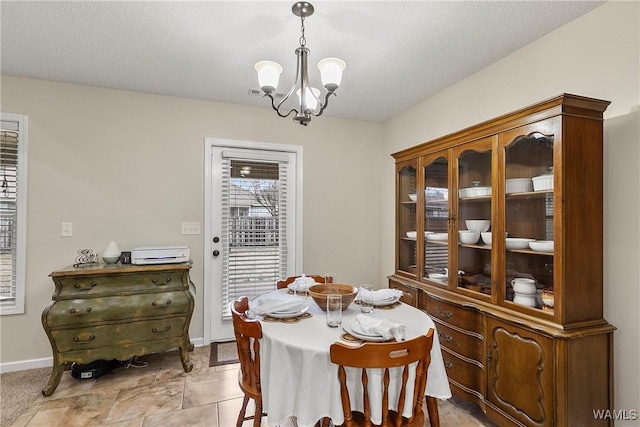 dining area featuring baseboards, visible vents, a chandelier, and a textured ceiling