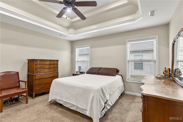 bedroom featuring visible vents, a tray ceiling, a ceiling fan, and light colored carpet