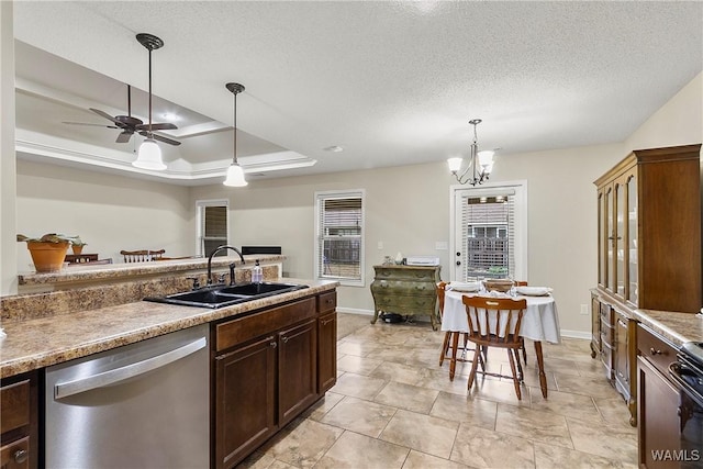 kitchen with a textured ceiling, a sink, stainless steel dishwasher, a tray ceiling, and decorative light fixtures