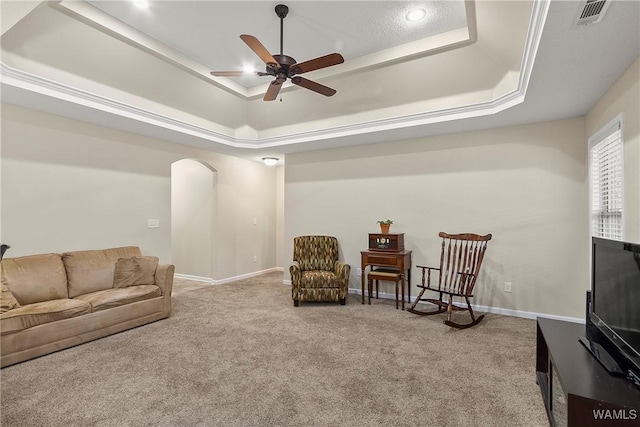 living area featuring a tray ceiling, carpet flooring, visible vents, and baseboards