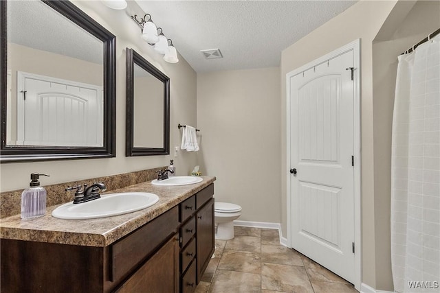 bathroom featuring a textured ceiling, toilet, a sink, and visible vents