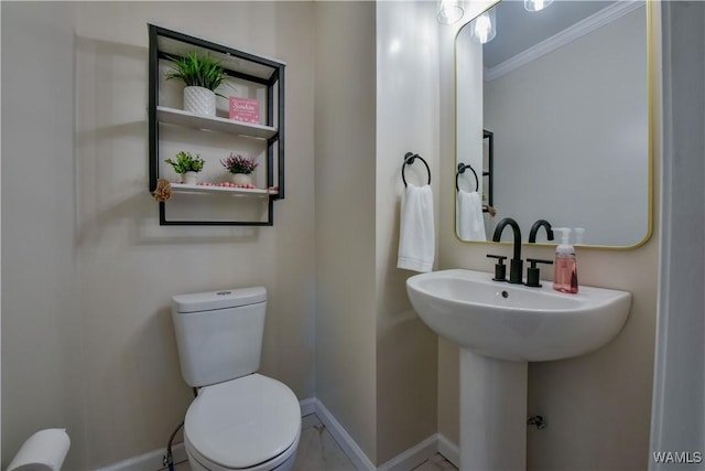 bathroom with toilet, a sink, baseboards, and crown molding