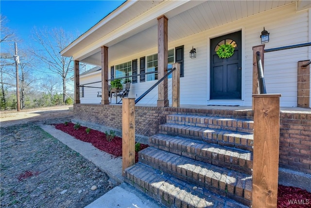 property entrance with covered porch and brick siding