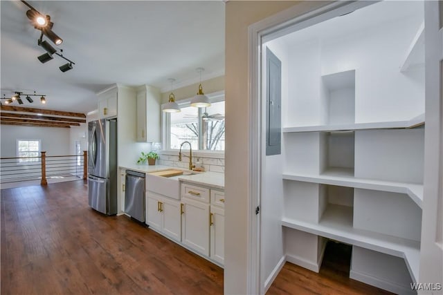 kitchen featuring stainless steel appliances, a sink, white cabinets, dark wood-style floors, and tasteful backsplash