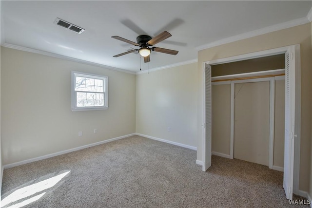 unfurnished bedroom featuring carpet floors, a closet, visible vents, ornamental molding, and baseboards