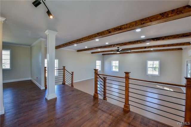 spare room featuring wood finished floors, a healthy amount of sunlight, baseboards, beam ceiling, and decorative columns