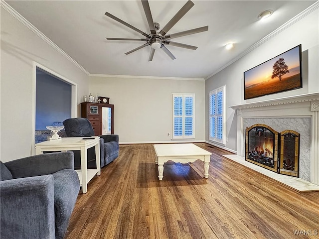 living room with a fireplace, crown molding, wood-type flooring, and ceiling fan