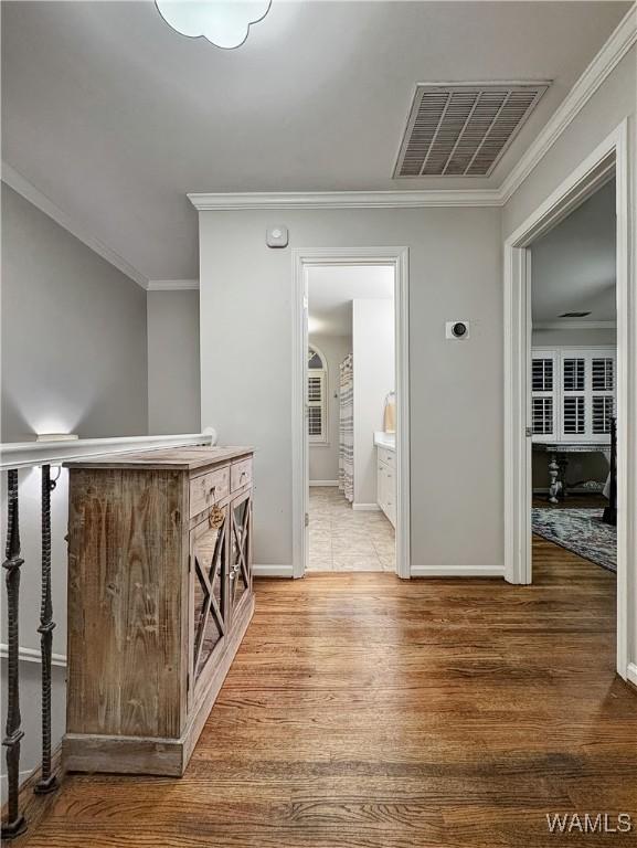 corridor with hardwood / wood-style floors and ornamental molding