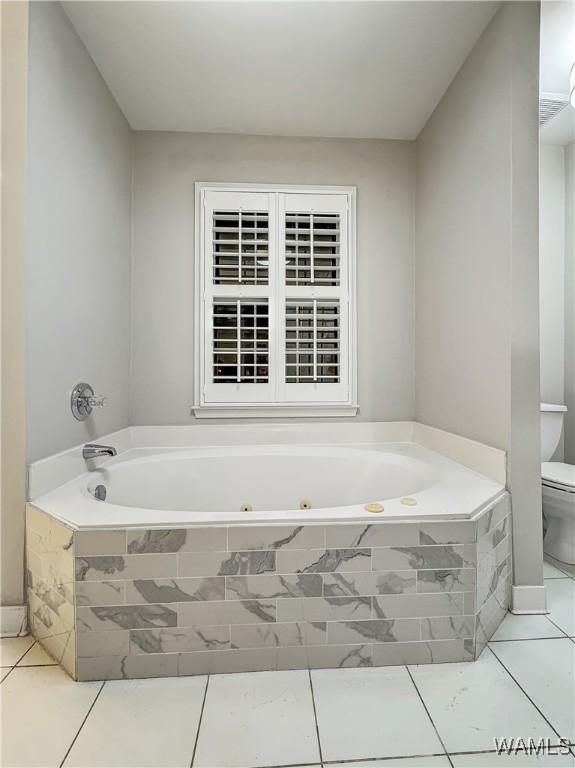 bathroom featuring tiled tub and toilet