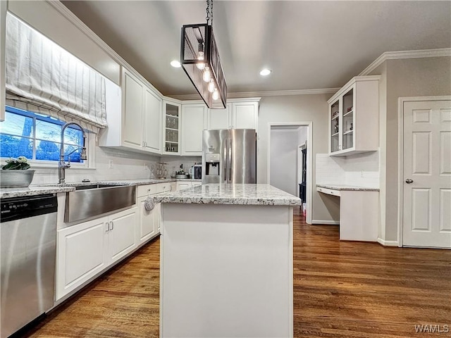 kitchen with sink, crown molding, a center island, stainless steel appliances, and white cabinets