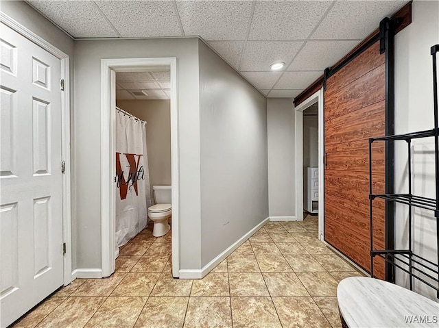 bathroom with a paneled ceiling, toilet, and tile patterned flooring