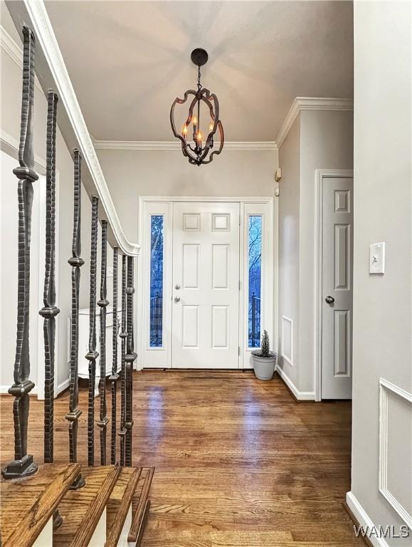 foyer featuring hardwood / wood-style floors, crown molding, and a chandelier