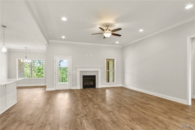 unfurnished living room with hardwood / wood-style flooring, ceiling fan with notable chandelier, ornamental molding, and a tile fireplace