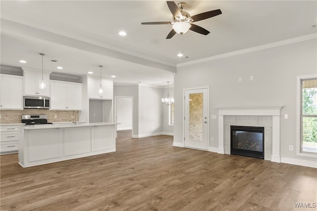 kitchen with pendant lighting, a kitchen island with sink, appliances with stainless steel finishes, white cabinetry, and wood-type flooring