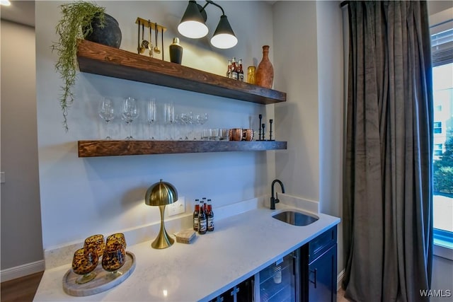 bar featuring wine cooler, indoor wet bar, a sink, and baseboards