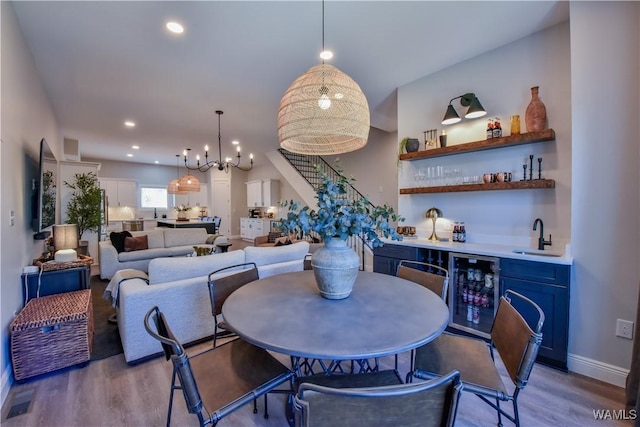 dining area featuring wine cooler, recessed lighting, wet bar, and wood finished floors