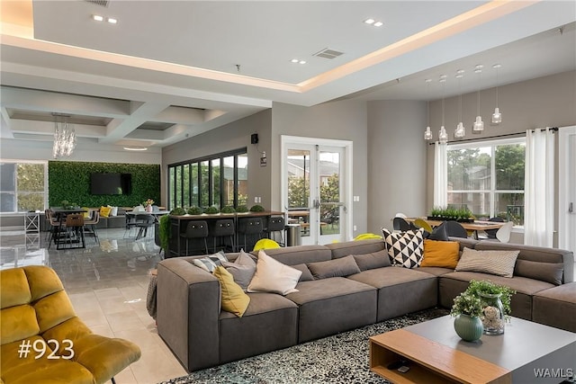 living area with light tile patterned flooring, a healthy amount of sunlight, visible vents, and coffered ceiling