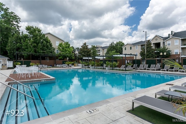 community pool featuring a residential view, a patio, and fence