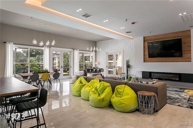 tiled living area featuring a glass covered fireplace, french doors, and visible vents