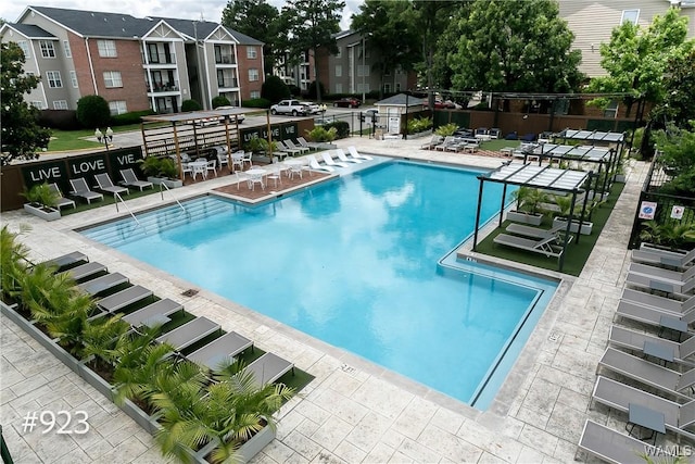 community pool with a patio area and fence