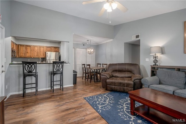 living area featuring visible vents, ceiling fan with notable chandelier, lofted ceiling, and wood finished floors