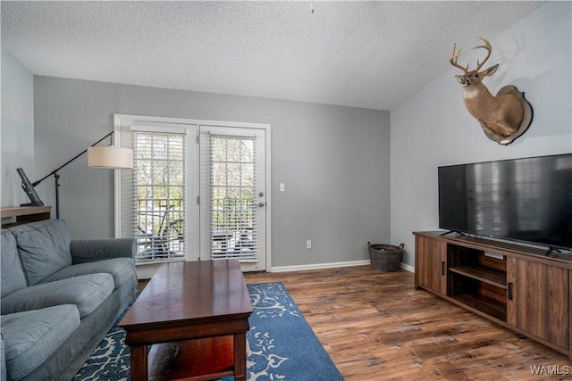 living area featuring wood finished floors, baseboards, and a textured ceiling