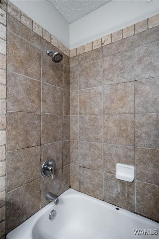 bathroom with tub / shower combination and a textured ceiling