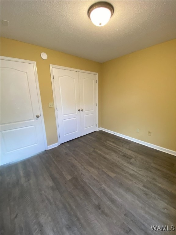 unfurnished bedroom featuring a textured ceiling, dark hardwood / wood-style floors, and a closet