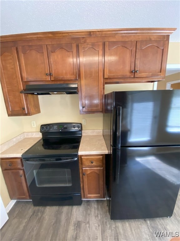 kitchen with dark hardwood / wood-style flooring and black appliances