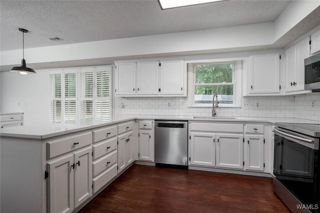 4410 Nicholas Ave, Northport, AL 35473 - kitchen with stainless steel appliances, a peninsula, dark wood-style floors, decorative backsplash, and a textured ceiling