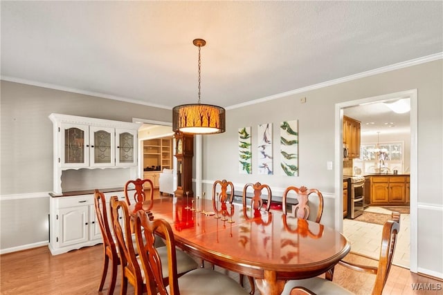 dining area featuring crown molding and light hardwood / wood-style flooring