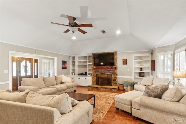 living room with a fireplace, lofted ceiling, crown molding, light wood-type flooring, and built in shelves