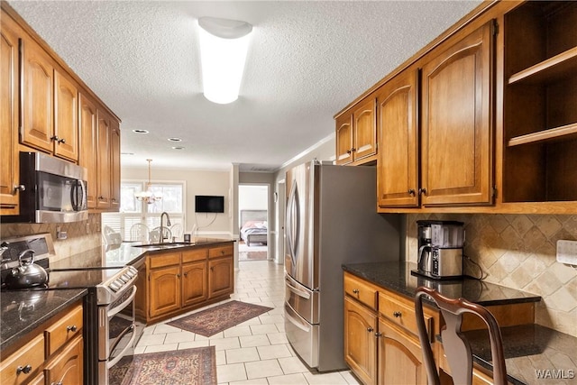 kitchen with appliances with stainless steel finishes, tasteful backsplash, sink, hanging light fixtures, and light tile patterned floors